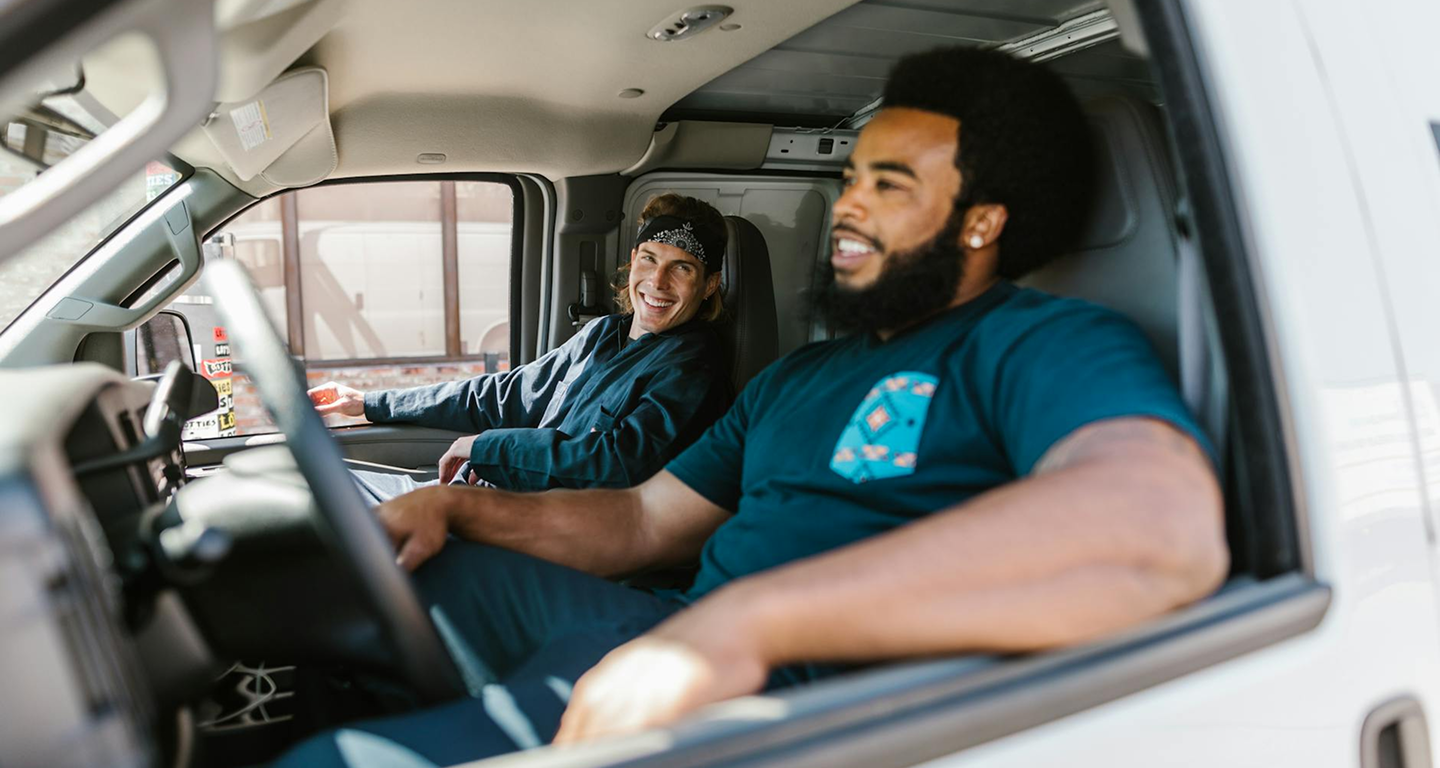 two men smiling in a minibus
